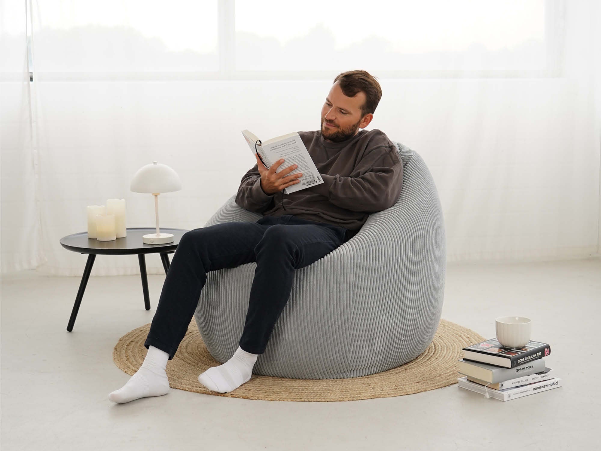 Sitzsack aus Cord in hellgrau. Mann sitzt auf Sitzsack und liest ein Buch 