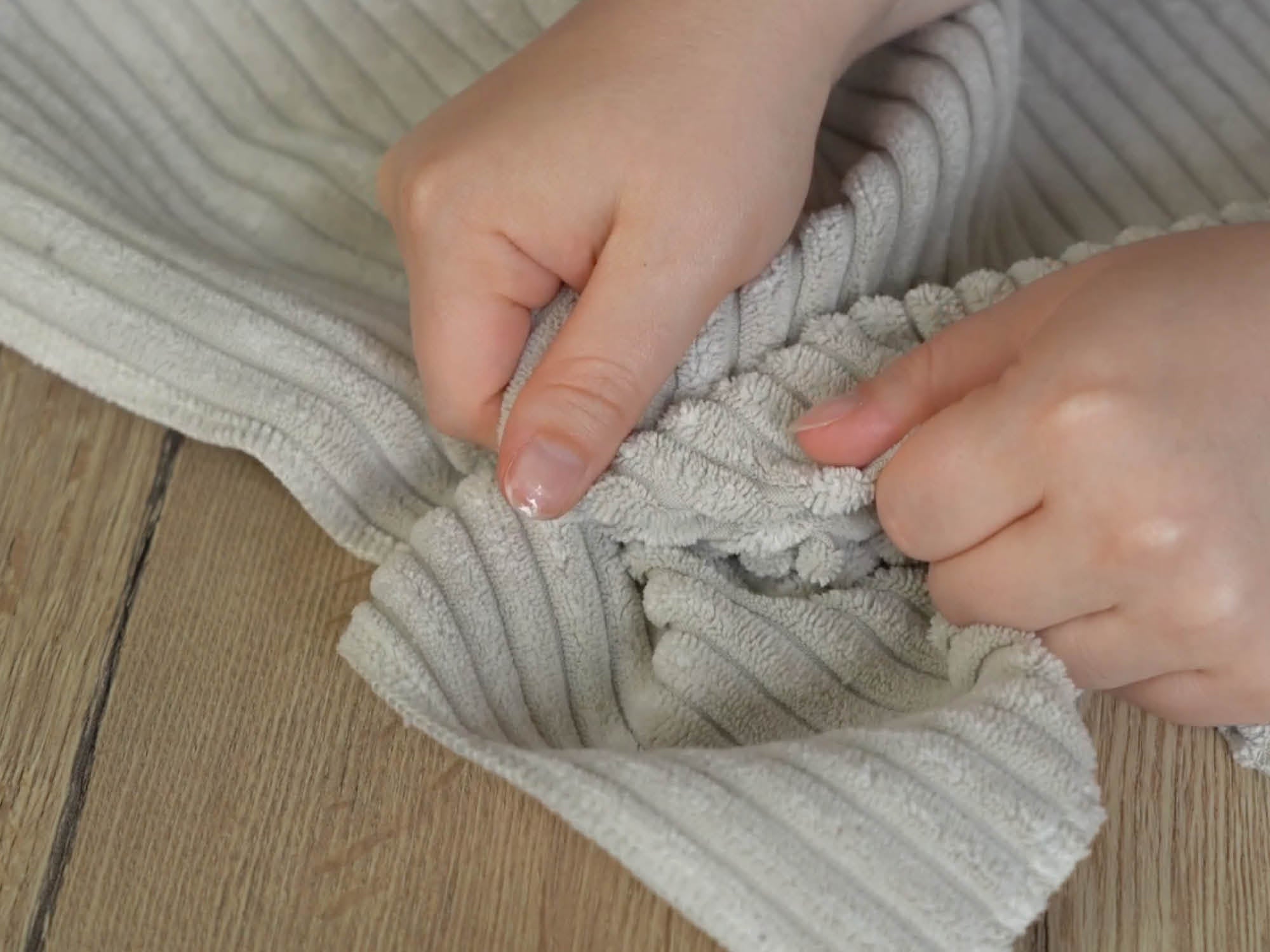 zwei Hände haben Cordstoff in beige in der Hand und greifen in den Stoff 