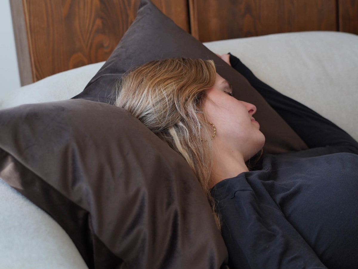Großes XXL Kissen aus Samt 'Hug' auf einem Sofa, Frau liegt mit dem Kopf auf dem Kissen und schläft 
