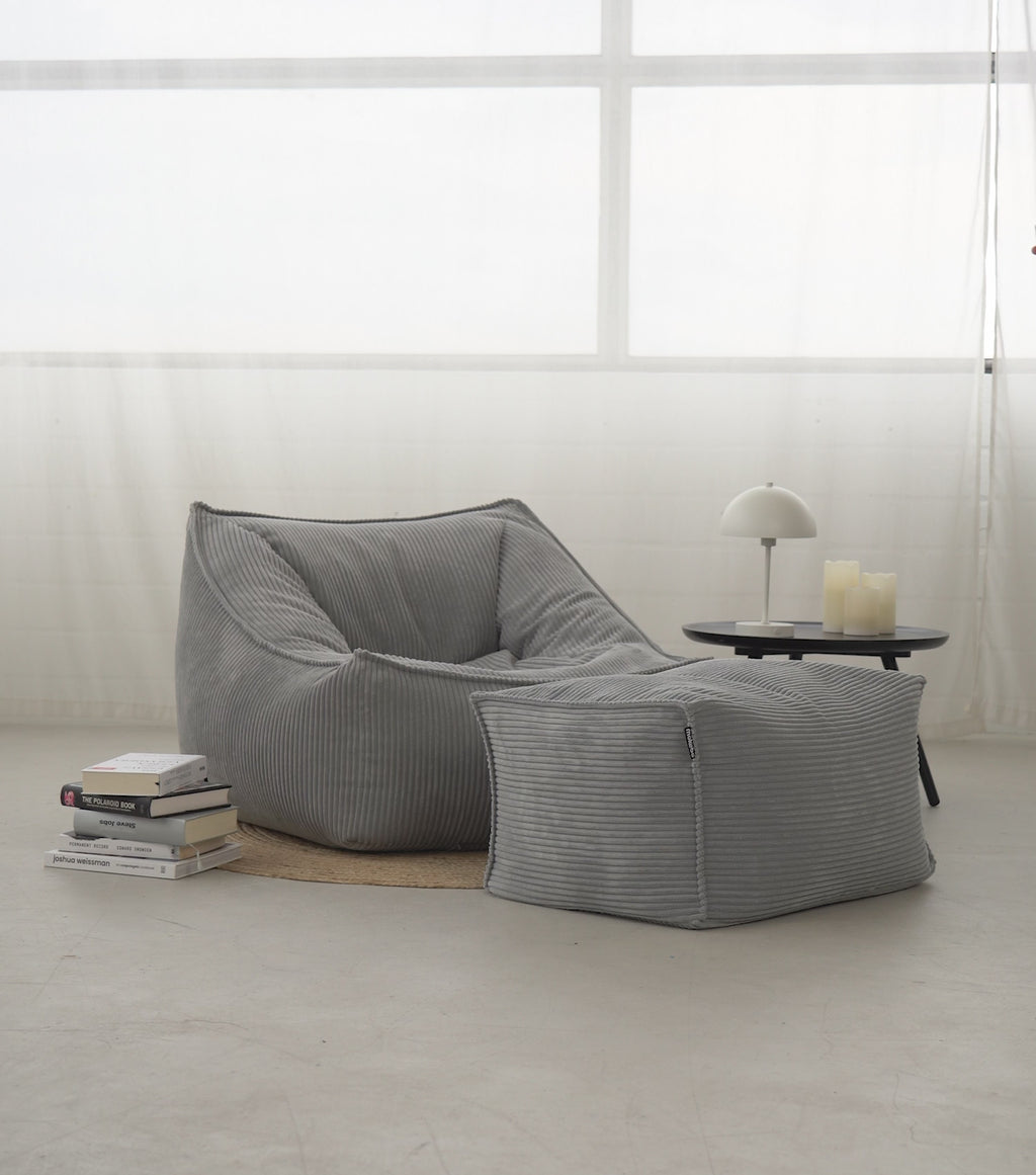 Produktvideo Sitzsack Sitzsessel 'Der Lümmel' aus Cord in grau. Mann setzt sich mit einer Tasse auf den Sitzsack, liest ein Buch, streicht über den Stoff und steht vom Sitzsack auf. 